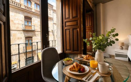 a table with food on it in a room with a window at Rua Mayor MSuites in Salamanca