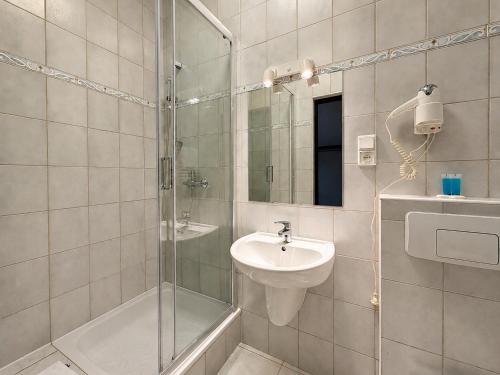 a bathroom with a glass shower and a sink at Centrum Konferencyjno-Apartamentowe Mrówka in Warsaw