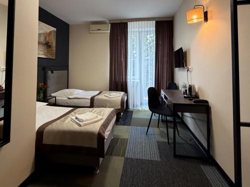 a hotel room with two beds and a desk at Centrum Konferencyjno-Apartamentowe Mrówka in Warsaw