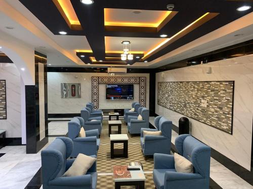 a waiting room with blue chairs and a flat screen tv at الشرفة هوم للشقق المخدومة in Najran