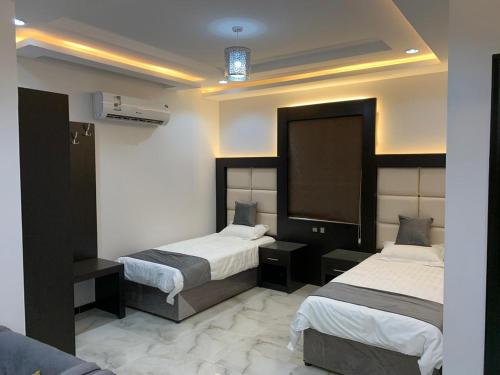 a hotel room with two beds and a tv at الشرفة هوم للشقق المخدومة in Najran