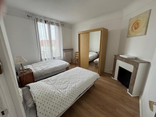a bedroom with two beds and a fireplace at Le GIGI in Antony