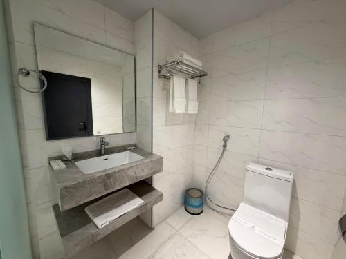 a white bathroom with a toilet and a sink at Burj Al Salam Hotel in Al ‘Alwīyah