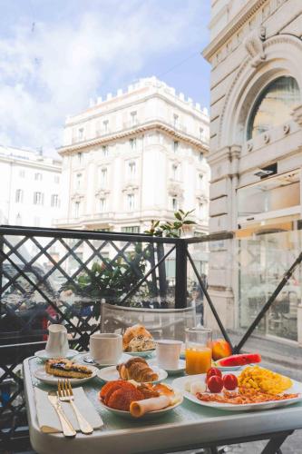 a table with plates of food on a balcony at Hotel Fellini a Fontana di Trevi in Rome