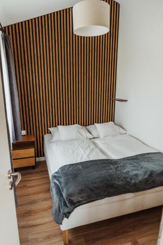 a bedroom with a white bed with a wooden wall at Faház- Naplemente in Véménd