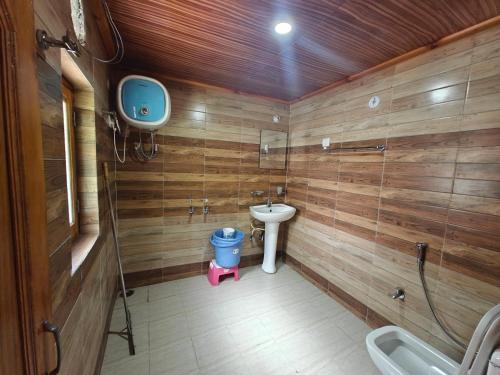 a bathroom with wooden walls and a toilet and a sink at Himalaya Vista - 1km Uphill Hike from Main Road in Harsil