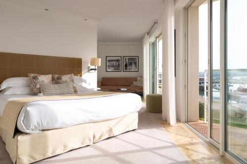 a bedroom with a large bed and a large window at Hôtel La Marine - Restaurant Marnage in Barneville-Carteret