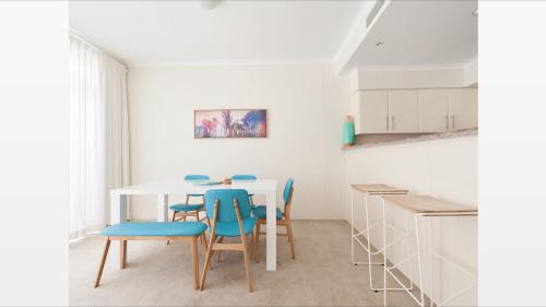 a kitchen with a white table and blue chairs at Seaspray Villa 5 in Shoal Bay