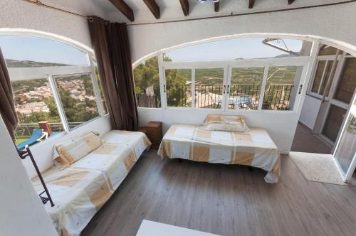 a bedroom with two beds and a large window at El Balcón de La Safor - Llumicel in Ador