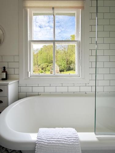a white bath tub in a bathroom with a window at Foresters Cottage, Dalry in Dalry