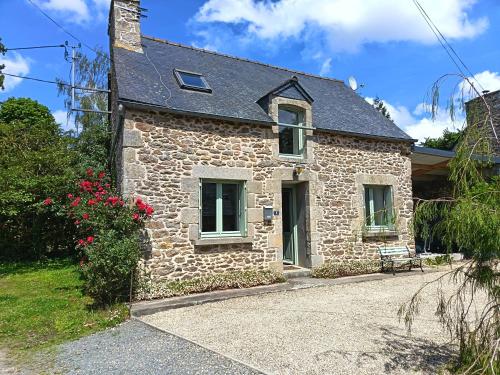 a stone house with a bench in front of it at Maison Bretagne in Bourseul