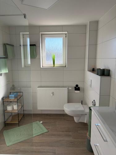 a bathroom with a toilet and a window with a potted plant at Ferienwohnung RaHo in Wadgassen