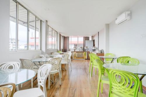 a cafeteria with white tables and green chairs at Hotel Pratishtha in Guwahati