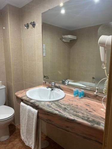 a bathroom with a sink and a toilet and a mirror at Hotel Brasa in Elvas