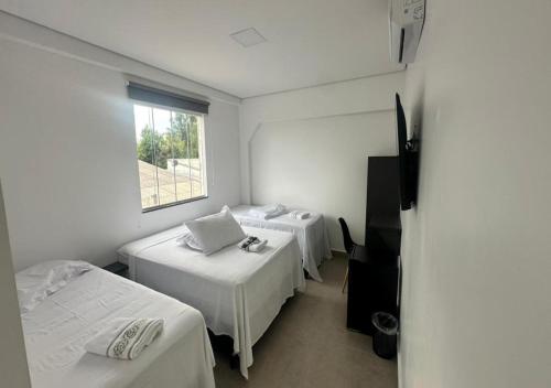 a room with two beds and a window at Hotel Rota Dos Tropeiros in Castro