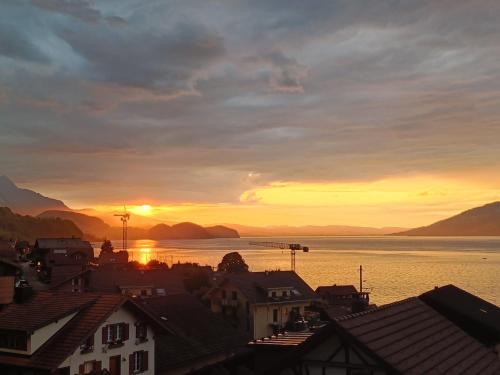 a sunset over a town with houses and the water at Thimo's Lakeview - Sunset near Interlaken in Leissigen