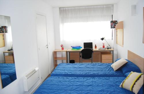 a bedroom with two beds and a desk with a computer at Residencia Universitaria Resa Colegio de Cuenca in Salamanca