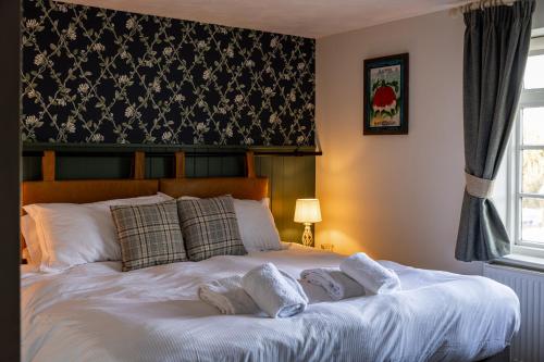 a bedroom with a white bed with two pillows at The Countryman Inn in Wool