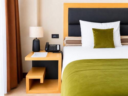 a hotel room with a bed and a phone on a table at Atera Business Suites in Belgrade