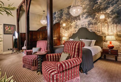 a hotel room with a bed and two chairs at Brownsover Hall Hotel in Rugby