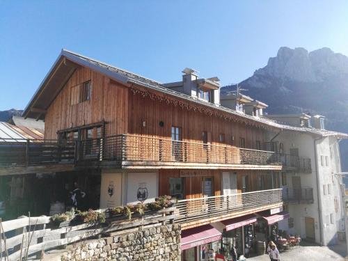 a large wooden building with a mountain in the background at Ciasa Savoy in Vigo di Fassa