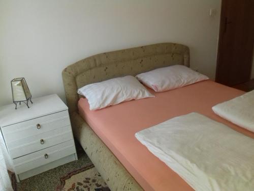 a bed with two pillows next to a night stand at Holiday Home Hodo in Sarajevo