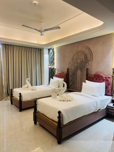 a bedroom with two beds with white sheets at Vetiver Grand in Jabalpur