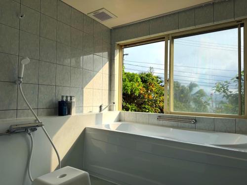 a bathroom with a bath tub and a window at Green Rabbit House by private beach in Ishigaki Island