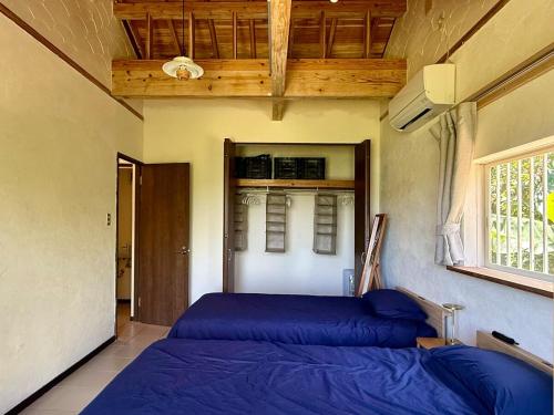 a bedroom with a blue bed and a window at Green Rabbit House by private beach in Ishigaki Island