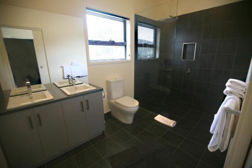 a bathroom with a toilet and a sink and a shower at New Norfolk Holiday Apartments in New Norfolk