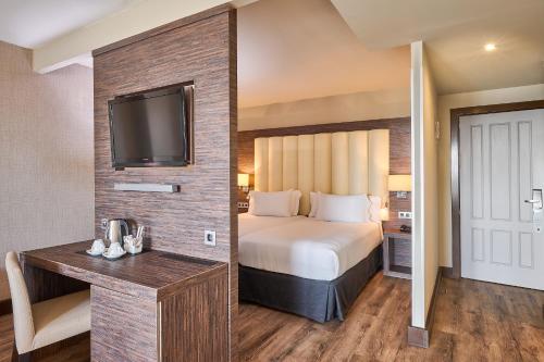 a hotel room with a bed and a flat screen tv at Gran Hotel Luna de Granada in Granada