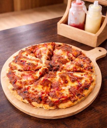 a pizza sitting on top of a wooden plate on a table at Infinite horizon nan in Ban San Khet Yao