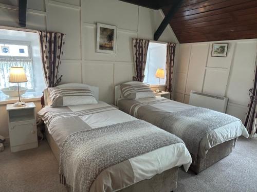 a bedroom with two beds and a window at Cummins Cottages in Ballycrossaun
