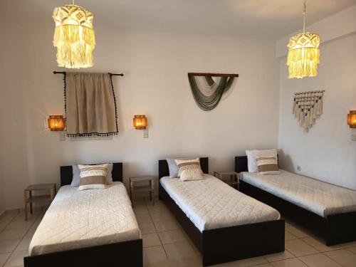 three beds in a room with lights on the wall at Sunshine in Maltezana
