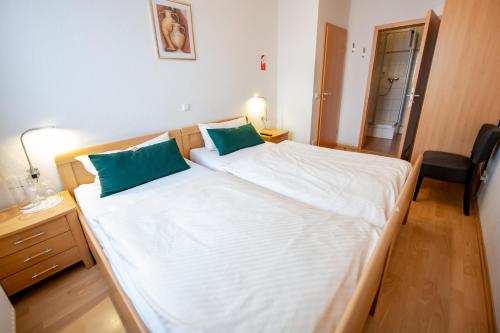 a bedroom with a large white bed with two green pillows at Hotel Gästehaus Lutgen in Waldfeucht
