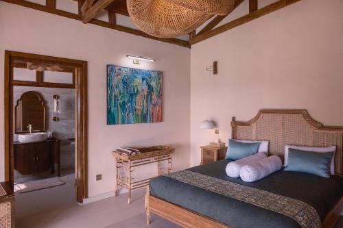 a bedroom with a bed and a bathroom with a sink at Villa Layan Hillside Residency with views and infinity pool in Amed in Ambat