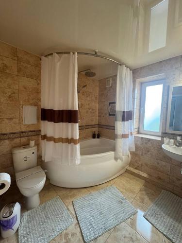 a bathroom with a tub and a toilet and a sink at Hotel DALIM in Duliby