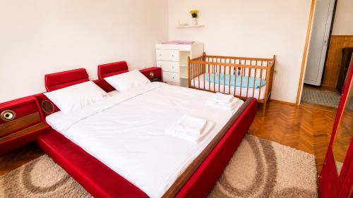 a bedroom with a red bed and a crib at Udoban porodični apartman ViS Raška, 80m2, parking, bašta in Raška