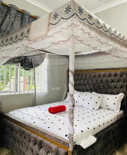 a white canopy bed with a red pillow on it at Triple A visitors in Kilindoni