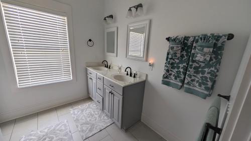 a white bathroom with a sink and a mirror at Sandnapper in Pawleys Island
