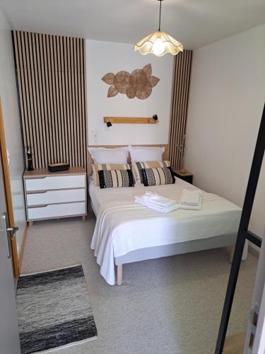 a bedroom with a white bed and a chandelier at Ty Colibri Lannion in Lannion