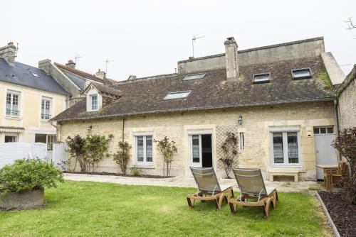 a house with two chairs in the yard at Les quatre vents in Luc-sur-Mer