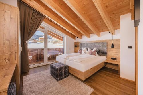 a bedroom with a large bed and a large window at Alpinium - inklusive SUPER SOMMER CARD in Fiss