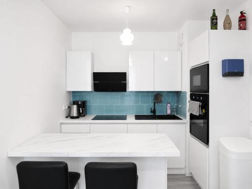 a white kitchen with white cabinets and black chairs at Noisiel appartement 2piece in Noisiel