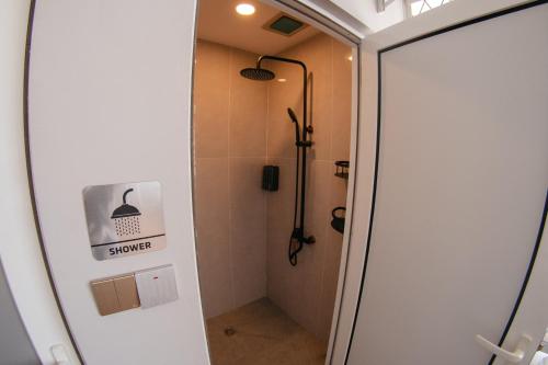 a bathroom with a shower stall and a shower door at Concrete Jungle Cabin in Kota Kinabalu