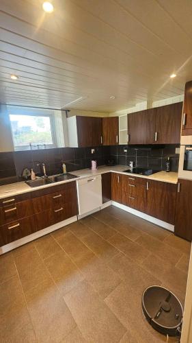 a large kitchen with wooden cabinets and a window at Leilighet med 2 soverom in Storen