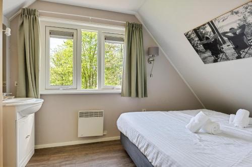 a bedroom with a bed and two windows at Bungalowpark Hoge Hexel in Hoge-Hexel
