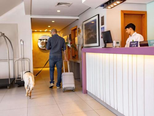 a man walking a dog in a pharmacy at Mercure Florianópolis in Florianópolis