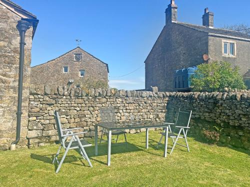 a table and chairs in front of a stone wall at Bradley House in Harrop Fold