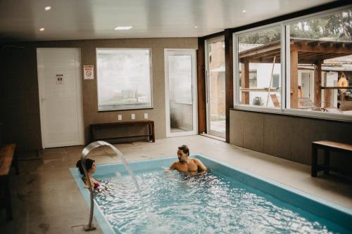 a man and a woman in a swimming pool at Pousada Recanto das Cerejeiras in Rio Grande